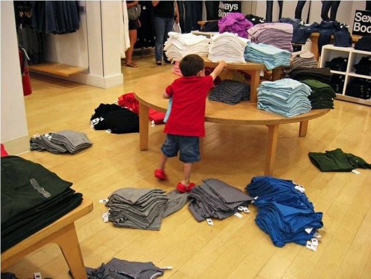 niño desacomodando la ropa de un estante y tirándola al suelo 