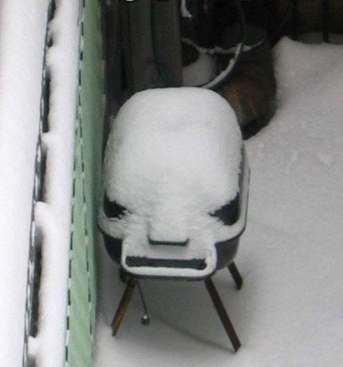 asador de carne cubierto de nieve en el patio de una casa 