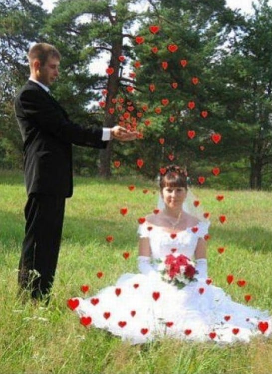 novios en un jardín mientras el novio le lanza corazones a la novia sentada en el pasto 