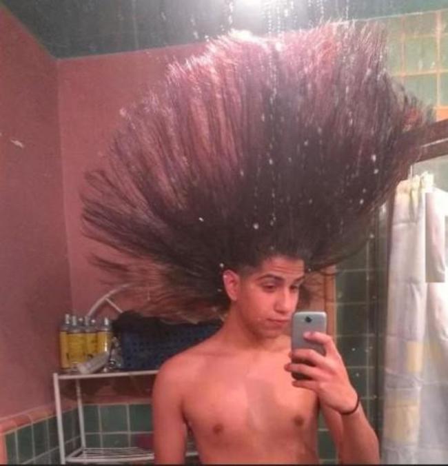 hombre tomándose una foto con el cabello erizado y levantado hacia el techo 