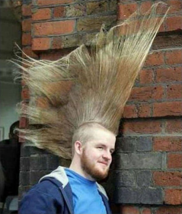 hombre con el cabello en moja largo recargado en una pared 