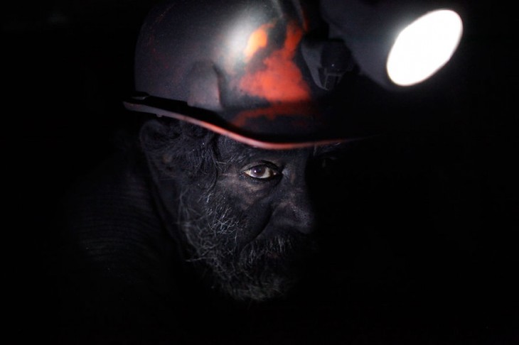 rostro de un hombre minero iluminado con la lampara de su casco