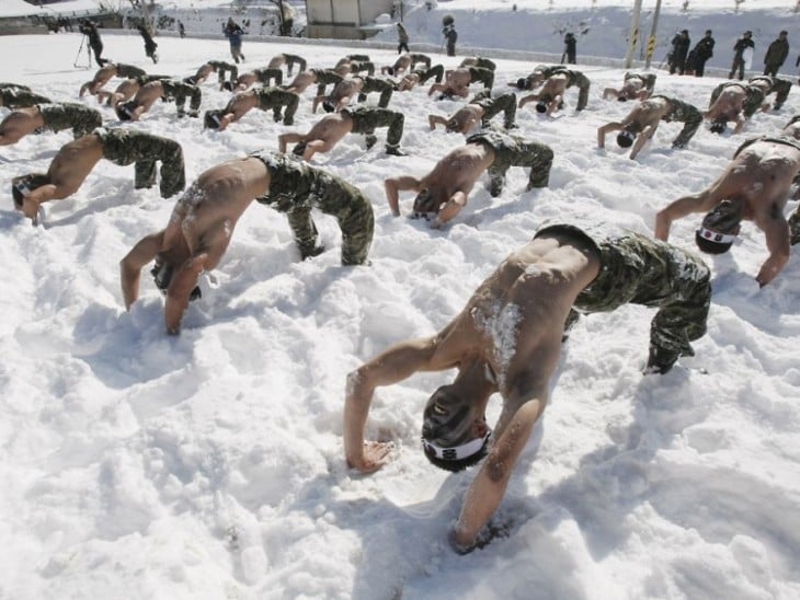 hombres semi recostados en la nieve durante un entrenamiento militar en Corea 