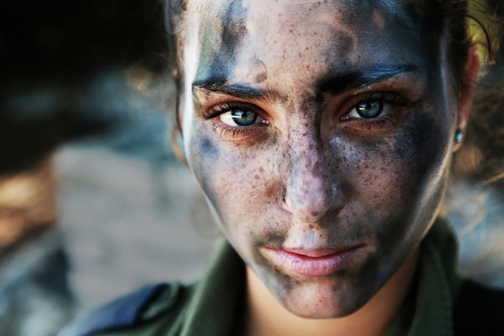 mujer de 18 años con el rostro cubierto de pintura de camuflaje militar 