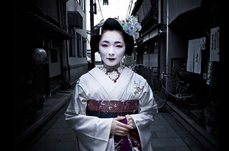 mujer vestida como geisha de color blanco en las calles de japón 