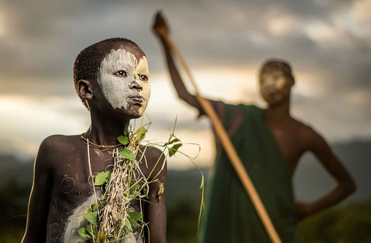 niños de una tribu africana usando vestidos verdes con ramas 