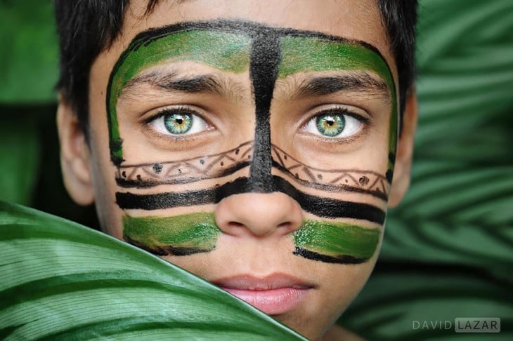 niño de ojos de color verde escondido entre las ramas 