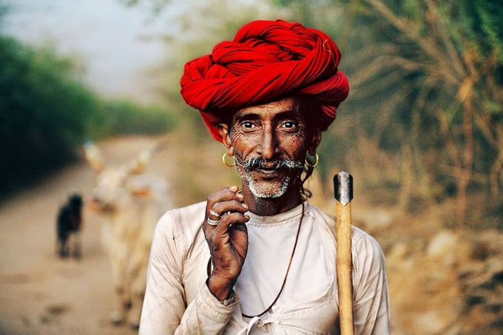 hombre rabari usando un turbante en la cabeza de color rojo mientras esta parado sobre un camino 