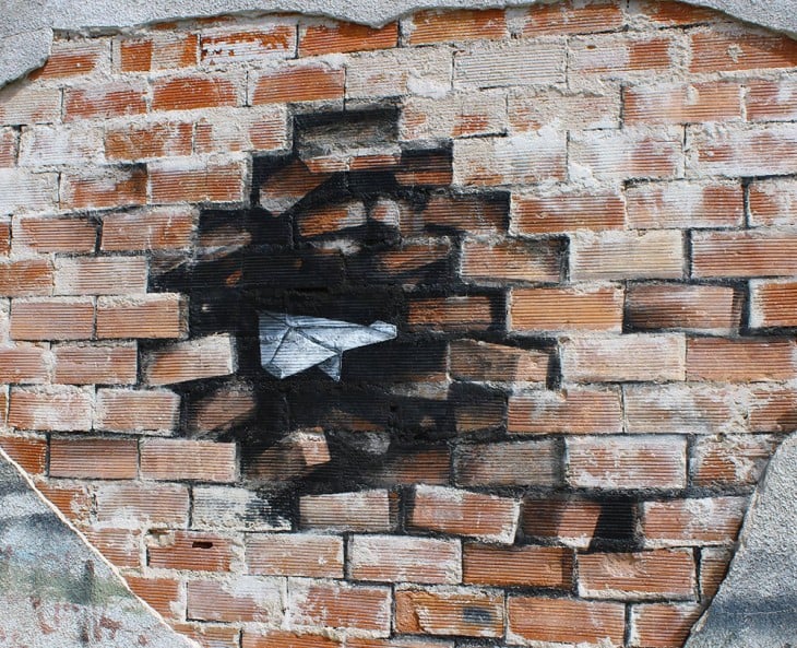 avioncito de papel en un muro de ladrillo 