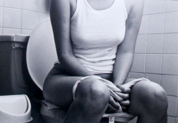 mujer sentada en la taza del baño con la ropa interior abajo