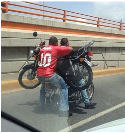 hombres en una solo moto cargan a otra moto