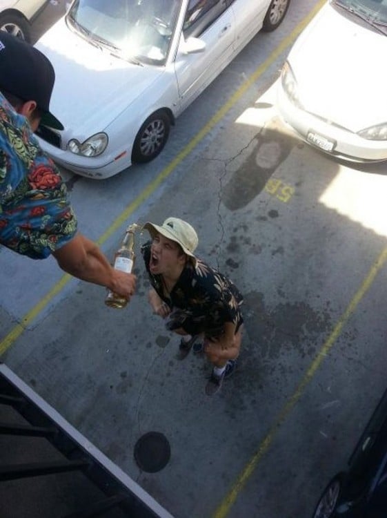 amigo dandole vino desde arriba a otro qu esta en el estacionamiento de un hotel