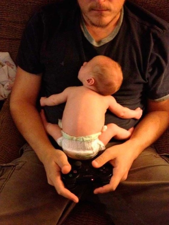 papa juega xbox con su bebe recien nacido en los brazos