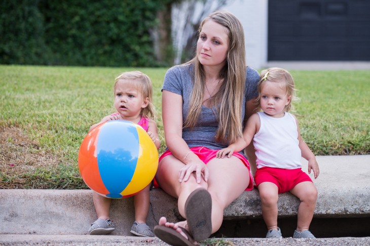 mujer sentada con sus hijas en la banqueta despues de haber jugado a la pelota