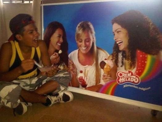 niño come un helado junto a un refrigerador con un poster de chicas riendose