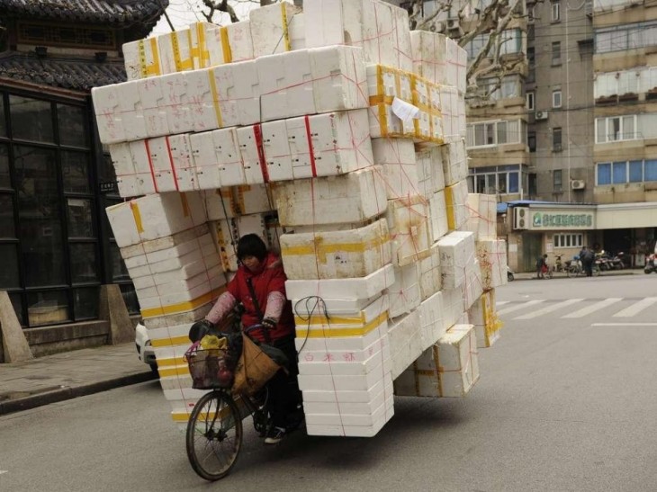 mujer cargando en la bici cajas de unicel