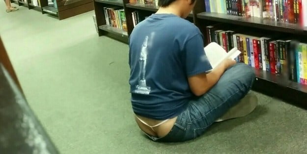 Hombre con tanga leyendo sentado en el piso