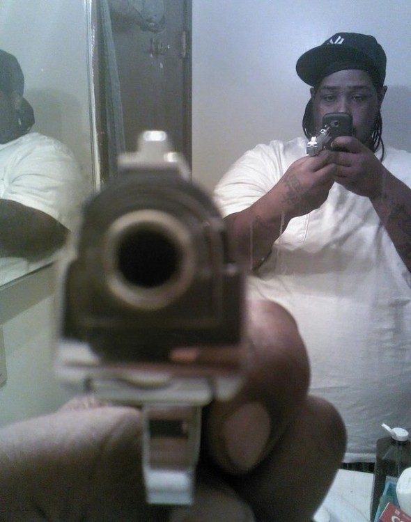 hombre de color con pistola se toma selfie apuntando al cañon