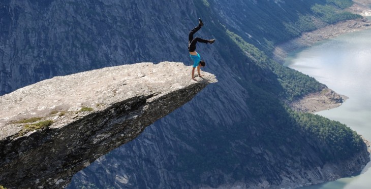 Chico parado de manos a la orilla de la TrollTunga en Noruega 