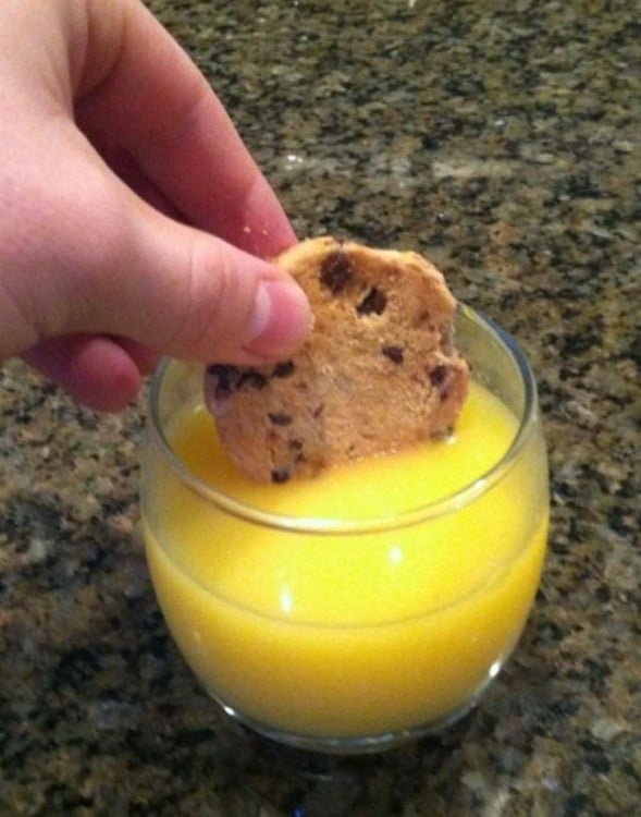 Mano sumergiendo una galleta en jugo 