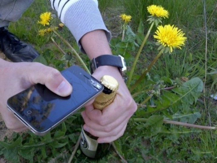 Persona abriendo una cerveza con un celular 