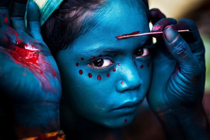 Manos pintando la cara de una niña 