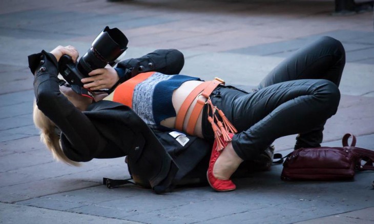 Fotógrafa casi acostada en el suelo 