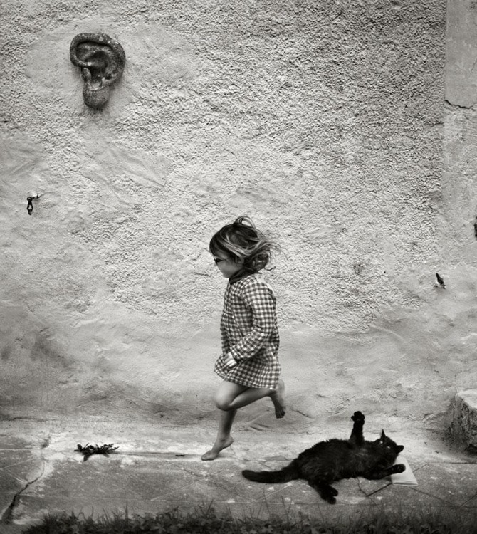 Niña brincando con un gato negro 