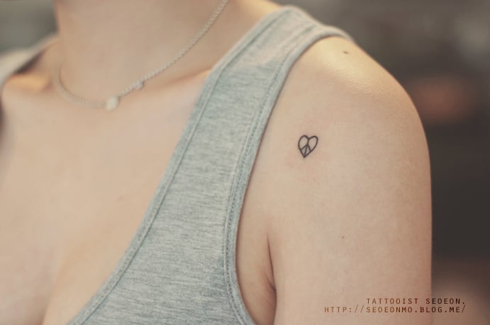 Tatuaje minimalista de corazón en el hombro de una chica 