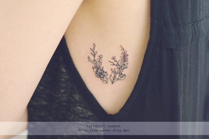 Tatuaje minimalista con flores en el pecho de una chica 