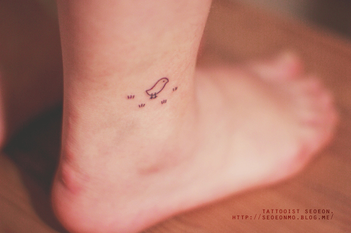 Tatuaje minimalista de pájaro en el pie de una persona 