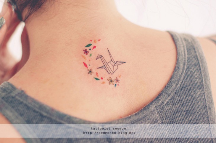 Tatuaje minimalista de origami en el cuello de una chica 