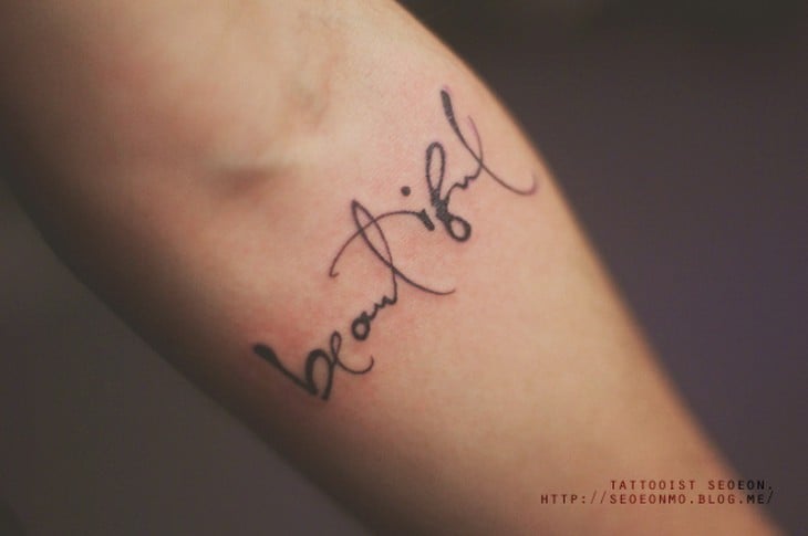 Tatuaje minimalista de frase en el brazo de una persona 