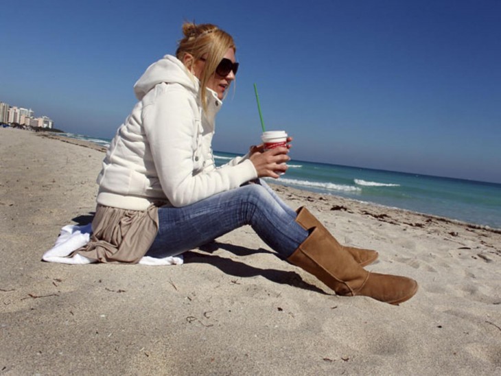 Chica en la playa con mucha ropa 