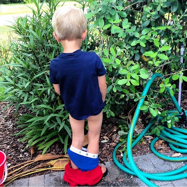 niño orinando en las plantas con todos los pantalones abajo