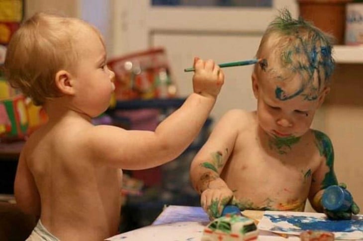 hermanito gemelo pintando la cara de su otro hermano con un marcador o brocha