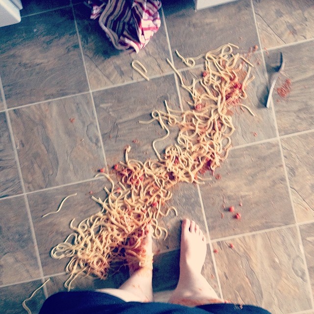 Spaghetti derramado en el suelo en los pies de una persona 