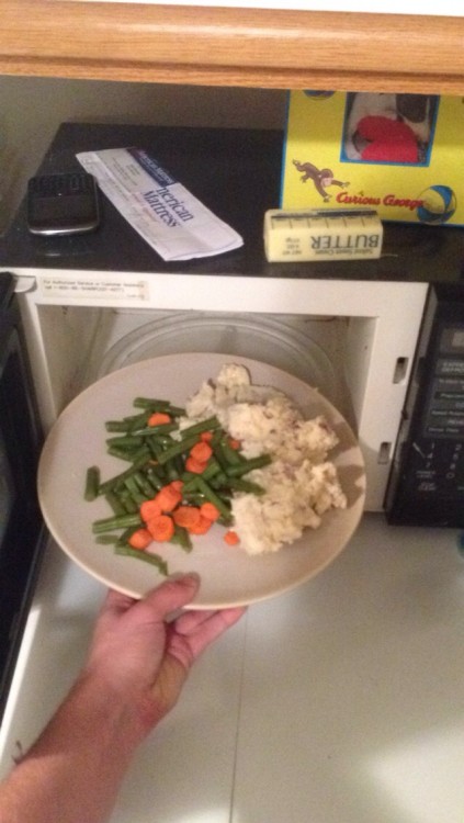 Persona intentando meter un plato que no cabe en el microondas 