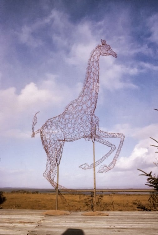 Escultura de alambre con la figura de una jirafa en color rojo 