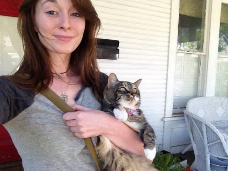 Una chica cargando a un gato y tomándose una selfie  