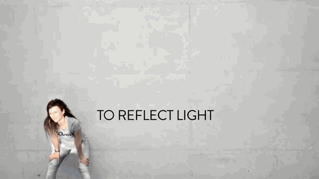 GIF de una chica reflejándose en la luz de un espejo en la pared
