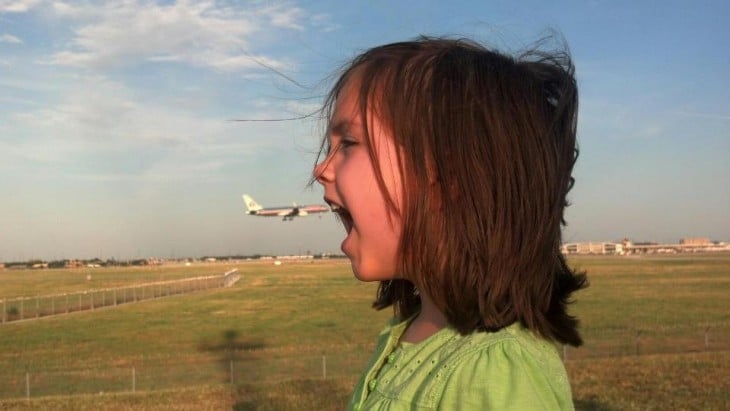 Foto tomada en el momento exacto donde un avión simula entrar a la boca de la niña 