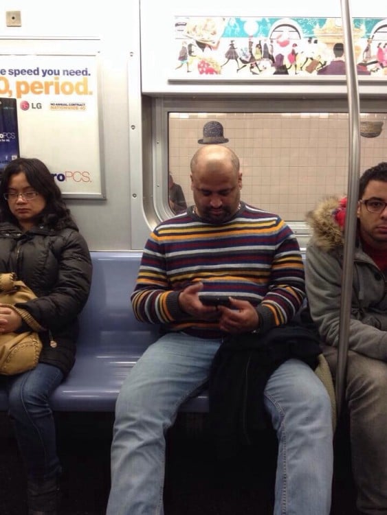 Hombre sentado en el transporte público que parece tener un sombrero sobe su cabeza 