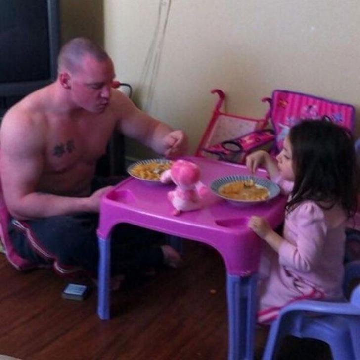 Padre e hija sentados en una pequeña mesa comiendo juntos 