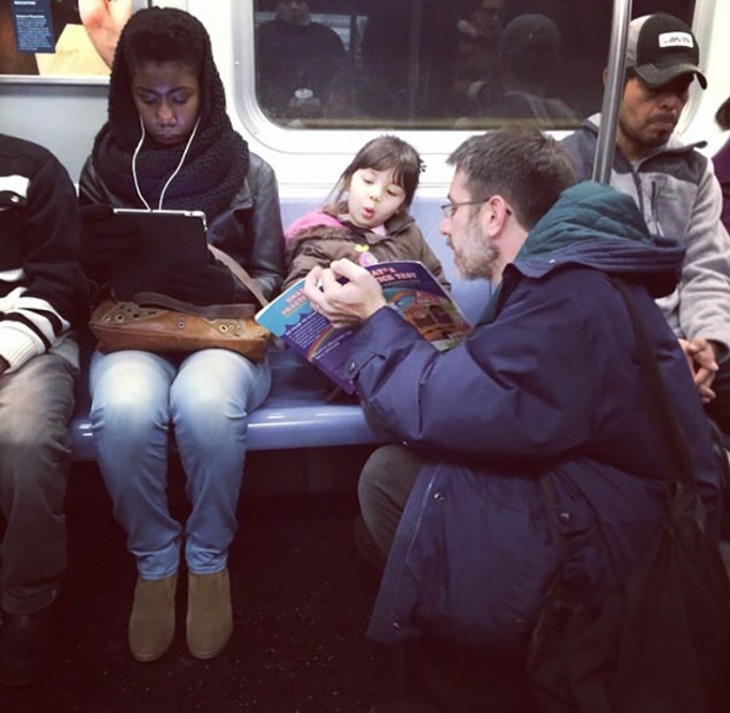 Personas en un transporte público y un padre mostrando un libro a su hija 