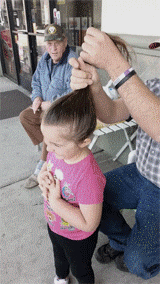 GIF de un padre peinando a su hija sujetando su cabello y la niña dando vuelta 