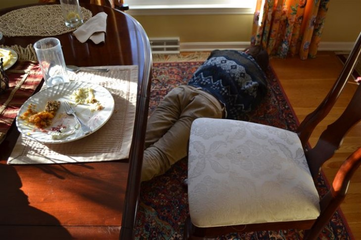 Hombre acostado en el piso debajo de una mesa después de comer 