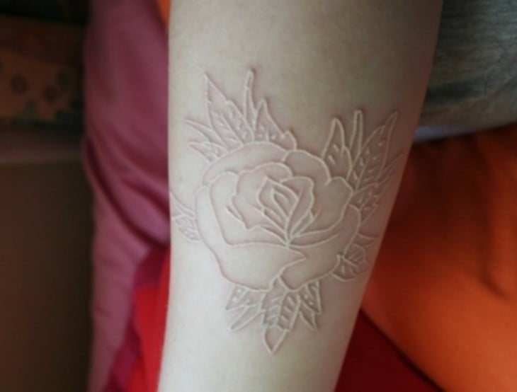 Tatuaje de una rosa sobre un brazo con tinta blanca 