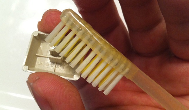 Cepillo de dientes limpiando una tecla de computadora 