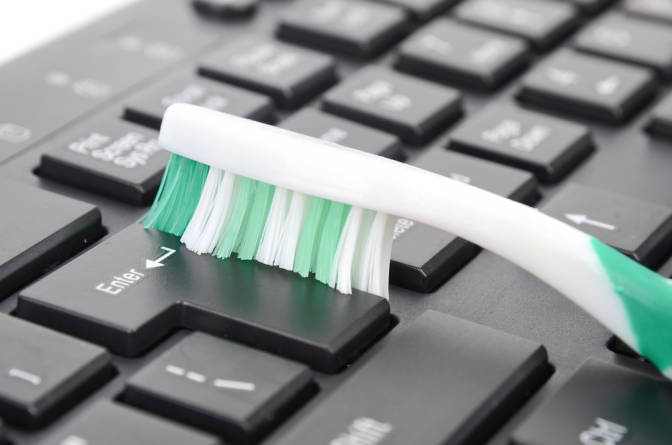 Cepillo de dientes limpiando el teclado de tu computadora 